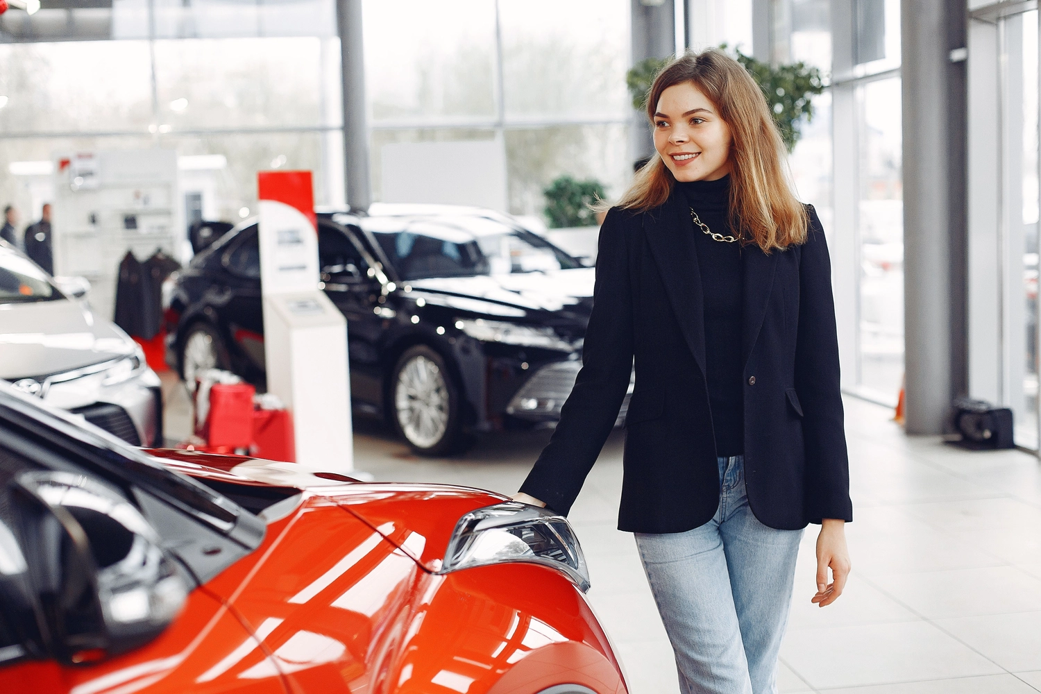 Stern Wagen GmbH -  Fahrzeug Einkauf - Selbstbewusste Frau begutachtet ein neues Auto in einem modernen Autohaus.