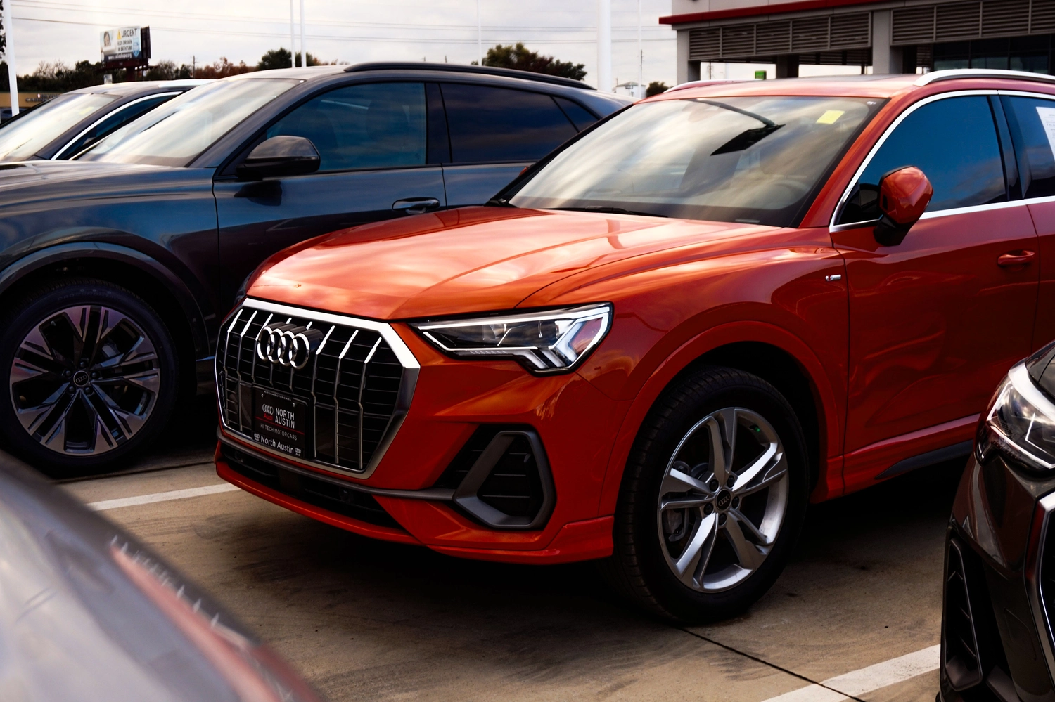 Stern Wagen GmbH -  Fahrzeug Einkauf - Ein eleganter roter Audi SUV wird auf dem Gelände eines Autohauses ausgestellt.